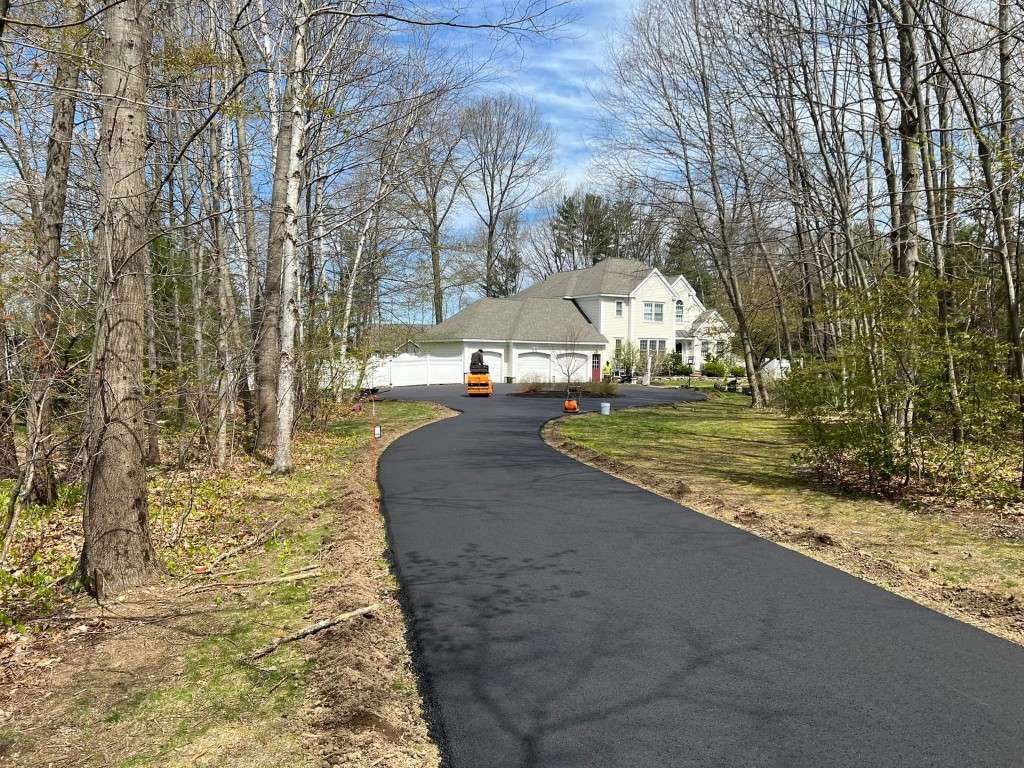 Asphalt driveway with a large house in the background