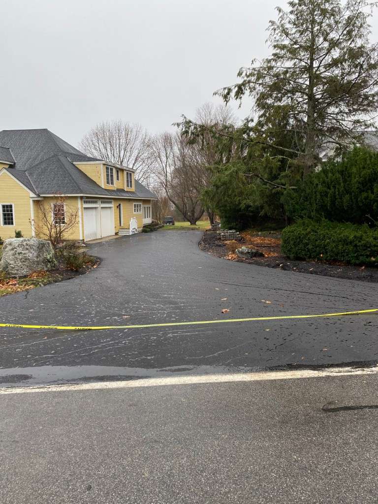 Crime scene tape surrounds a wet driveway leading to a house