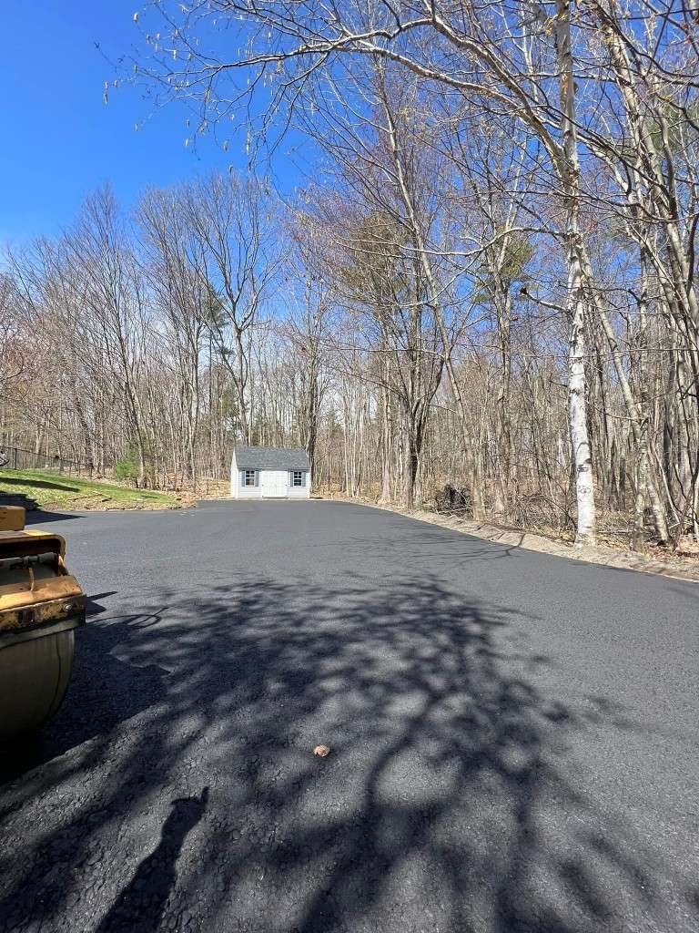 New asphalt driveway with a small house in background